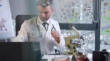 在临床实验室工作的迷人的、受人尊敬的白发男医生的正面视角，看显微镜和